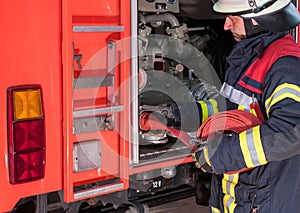 Firefighter in action connected a fire hose on the fire truck