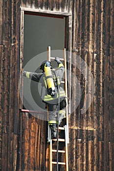Firefighter in action enters through a window to rescue people