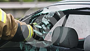 Firefighter beraking glass on car window extricate trapped victim from the car