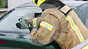 Firefighter beraking glass on car window extricate trapped victim from the car