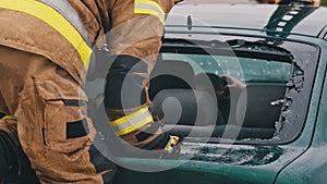 Firefighter beraking glass on car window extricate trapped victim from the car