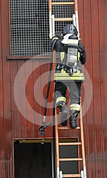 firefighter climbs the ladder with the oxygen cylinder to breath