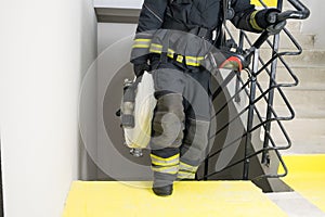 A firefighter climbs the stairs and carries a hose line and equipment for extinguishing fires indoors, front view