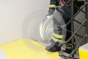 A firefighter climbs the stairs and carries a hose line and equipment for extinguishing indoor fires