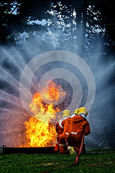 Firefighter Concept. Fireman using water and extinguisher to fighting with fire flame. firefighters fighting a fire with a hose an