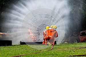 Firefighter Concept. Fireman using water and extinguisher to fighting with fire flame. firefighters fighting a fire with a hose an