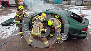 Firefighter cutting car doors with hydraulic cutter. Car accident