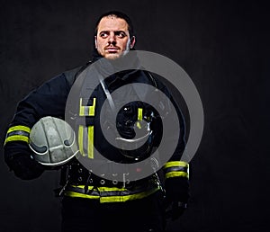 Firefighter dressed in uniform holds safety helmet.