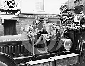 Firefighter driving a fire engine and a young woman sitting beside him