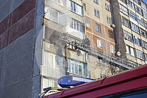 A firefighter extinguishes a balcony, in a high-rise building, from a telescopic ladder of a fire engine using a hydrant, against