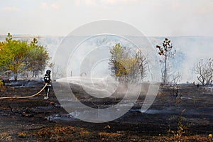 Firefighter extinguishes burning grass