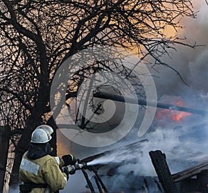 Firefighter extinguishes the fire. Fireman holding a hose with w photo