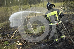 Firefighter extinguishes forest. Lifeguard pours water from hose. Work of rescue service