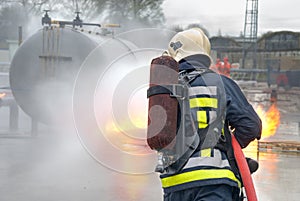 Firefighter extinguishing tank fire photo
