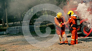 Firefighter fighting with flame using fire hose chemical water foam spray engine. Fireman wear hard hat, body safe suit uniform