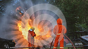 Firefighter fighting with flame using fire hose chemical water foam spray engine. Fireman wear hard hat, body safe suit uniform