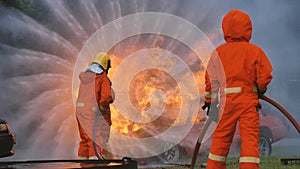 Firefighter fighting with flame using fire hose chemical water foam spray engine. Fireman wear hard hat, body safe suit uniform