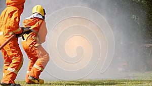 Firefighter fighting with flame using fire hose chemical water foam spray engine. Fireman wear hard hat, body safe suit uniform