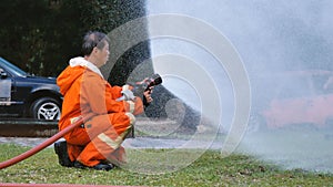 Firefighter fighting with flame using fire hose chemical water foam spray engine. Fireman wear hard hat, body safe suit uniform