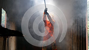 Firefighter fighting with flame using fire hose chemical water foam spray engine. Fireman wear hard hat, body safe suit uniform