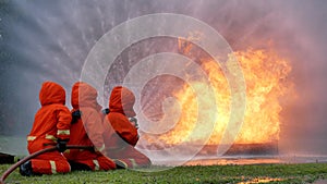 Firefighter fighting with flame using fire hose chemical water foam spray engine. Fireman wear hard hat, body safe suit uniform fo