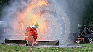 Firefighter fighting with flame using fire hose chemical water foam spray engine. Fireman wear hard hat, body safe suit uniform fo