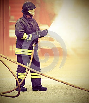 Firefighter during fire extinguishing and old toned effect