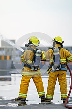 Firefighter or fireman team work water spray by high pressure nozzle to fire