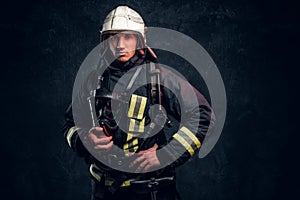 Firefighter in full protective equipment holding an oxygen mask and looking at a camera.