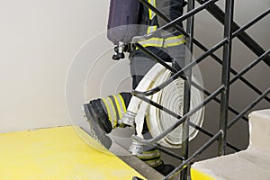 A firefighter goes down the stairs and carries a hose line and equipment for extinguishing fires in the room