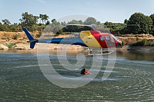 The firefighter helicopter filling the bucket at the lake
