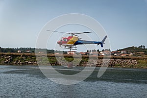 The firefighter helicopter filling the bucket at the lake