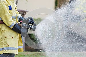 Firefighter holding high pressure fire hose nozzle.