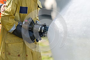 Firefighter holding high pressure fire hose nozzle.