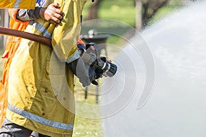 Firefighter holding high pressure fire hose nozzle.