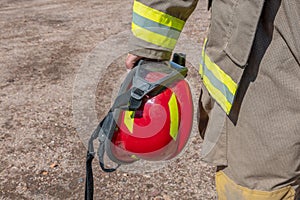 Firefighter holding red safety helmet. Horizontal photo