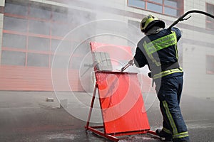 Firefighter with hose directs water on red shield. photo