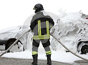 firefighter with hose while extinguishing the fire of the wrecke