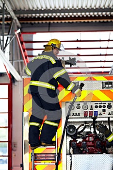 Firefighter, ladder and safety worker with hose truck at a fire station with emergency service employee. Uniform
