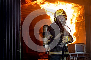 Firefighter man with protective and safety clothes stand with arm-crossed in front of fire on wall and ceiling in the kitchen