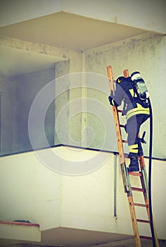 Firefighter with oxygen cylinder climbing a ladder with vintage