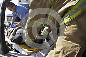 Firefighter And Paramedics Helping Car Crash Victim