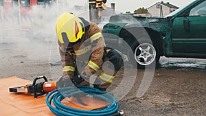 Firefighter preparing the hose wor hidraulic cutter on the car crash scene