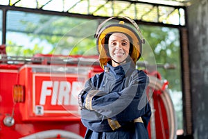 Firefighter with protective clothes stand with confidence action and smile in front of fire truck. She also smile with happy and
