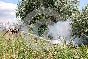 Firefighter in a protective suit among the grass.