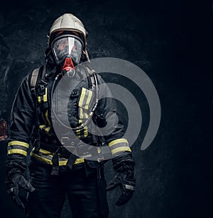 Firefighter in safety helmet and oxygen mask wearing protective clothes.