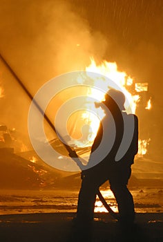 Bombero en silueta contra llamas 