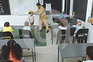 Firefighter teaching student about fire safety in classroom