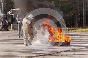 A fireman showing how to use a fire extinguisher on a training f