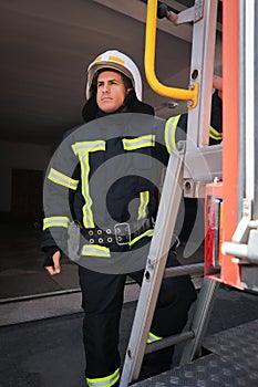 Firefighter in uniform and helmet near fire truck